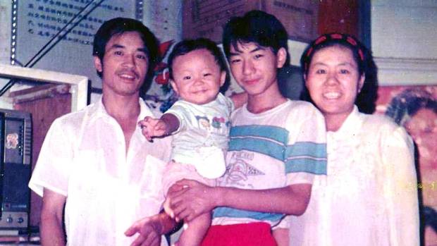 Na Foto: O bebê Jun Lin sendo segurado por um homem não identificado. Ao lado, seus pais.