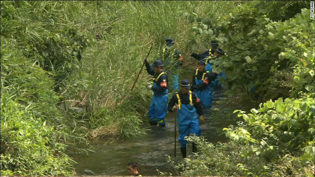 Na foto: Policiais japoneses fazem buscas em riacho na aldeia de  Créditos: CNN.