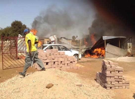 Na foto: Multidão incendeia a casa e carros do suposto serial killer. Créditos: Pretoria News.