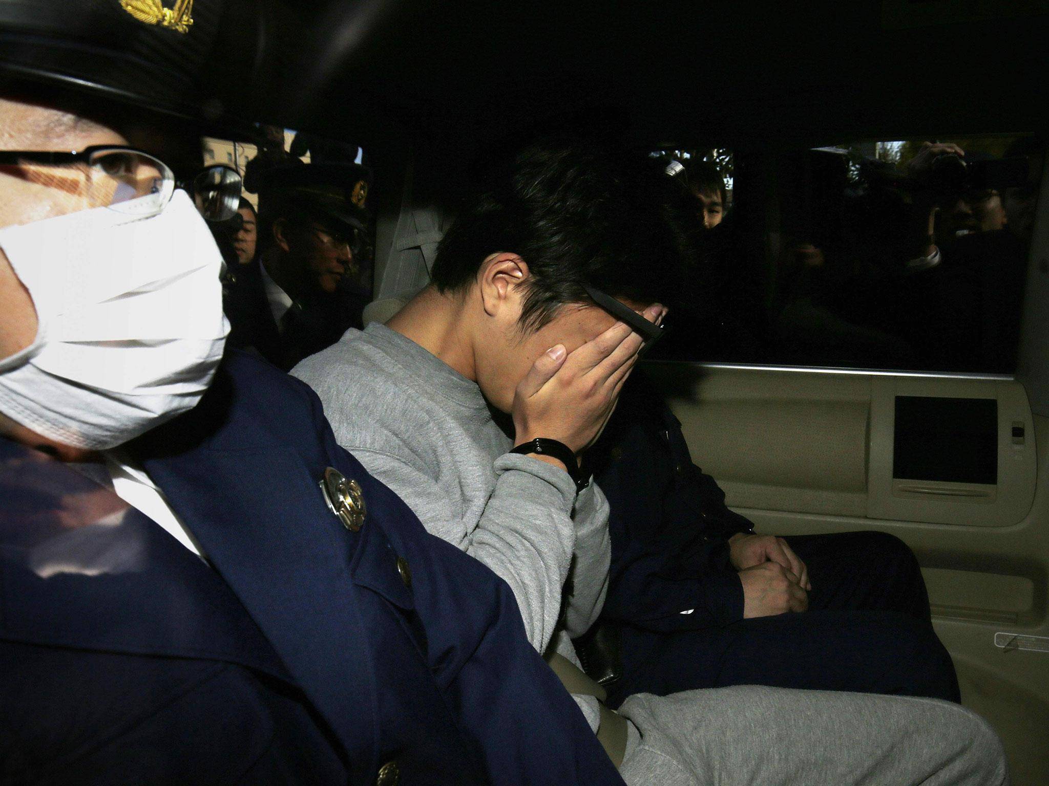 Takahiro Shiraishi esconde o rosto ao ser levado até o escritório do promotor público de Tóquio. Foto: Getty Images.